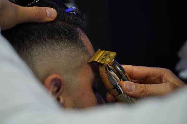 A trimmer held close to a skin fade, the blend already even from skin through to the longer top.