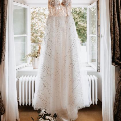 A wedding dress hanging in a sunlit window.