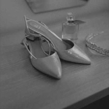 Shoes, perfume and a tiara set out on a dresser.