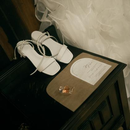 Shoes and an invitation on a dark nightstand.