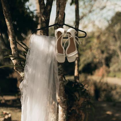 A veil and a pair of shoes hanging outdoors.