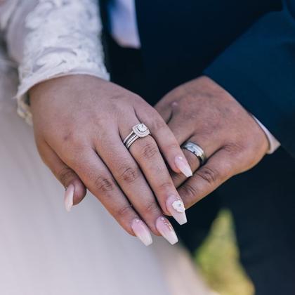 Two hands resting together, both wearing rings.