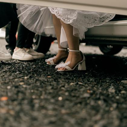 Shoes and the hem of a dress beside a car door.
