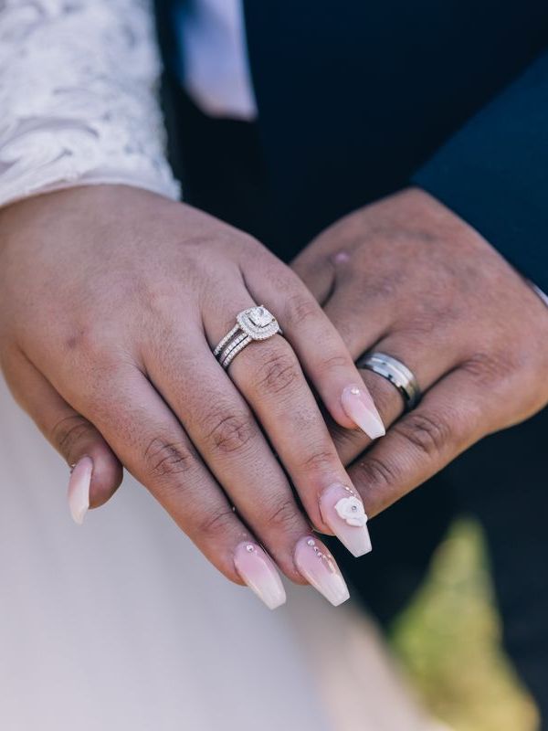 Two hands resting together after the ceremony, both wearing rings.